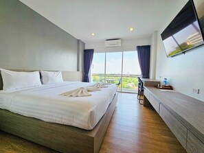 Une chambre d’hôtel avec un grand lit, un bureau, une télévision à écran plat et un balcon avec vue.