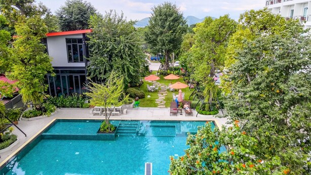 Ein Schwimmbecken, umgeben von üppiger Vegetation und Sitzgelegenheiten im Freien.
