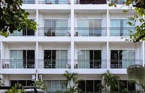 Un immeuble à plusieurs étages doté de balcons, de grandes fenêtres et de climatiseurs.