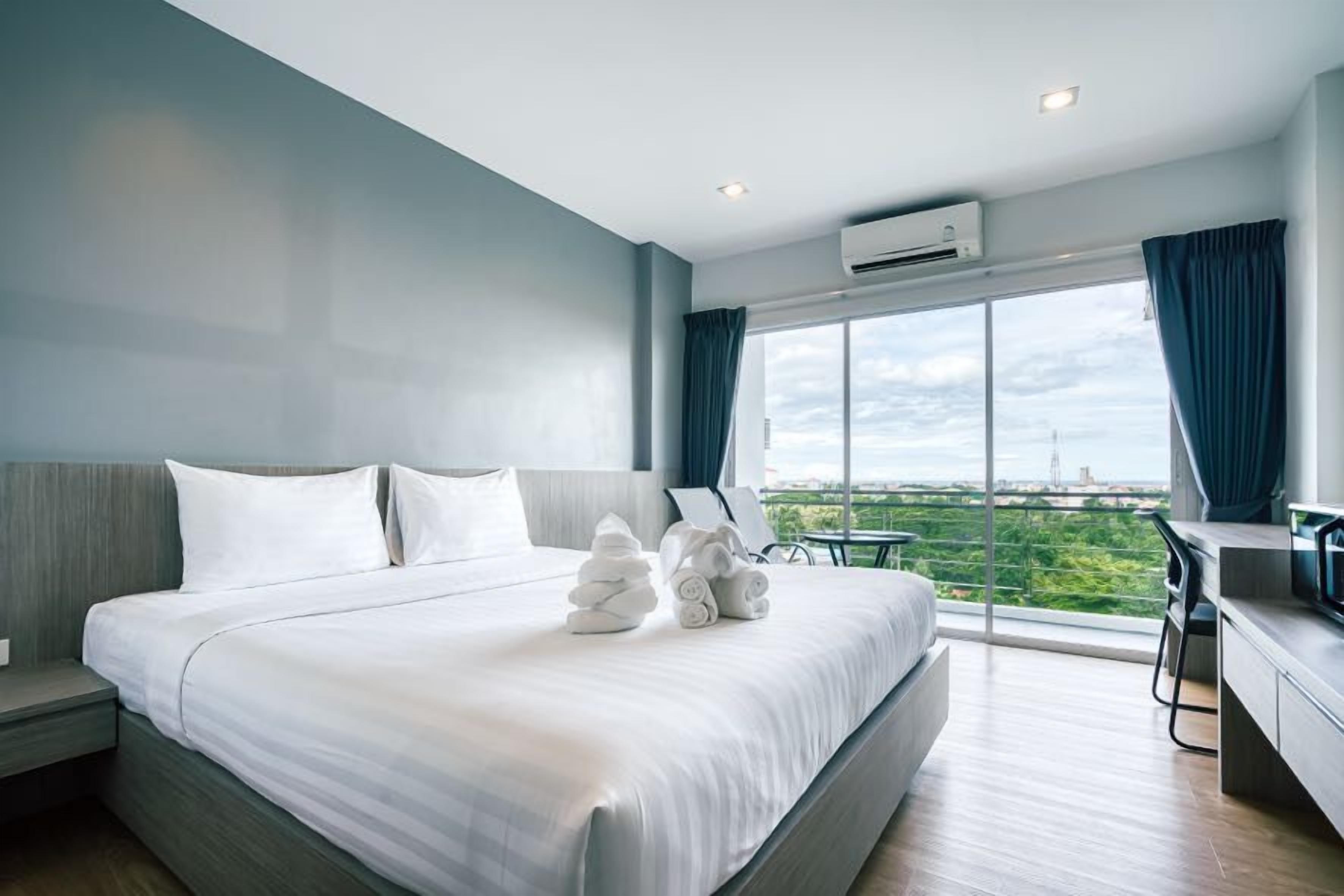 A modern hotel room with a large bed, a desk, and a view of the city.