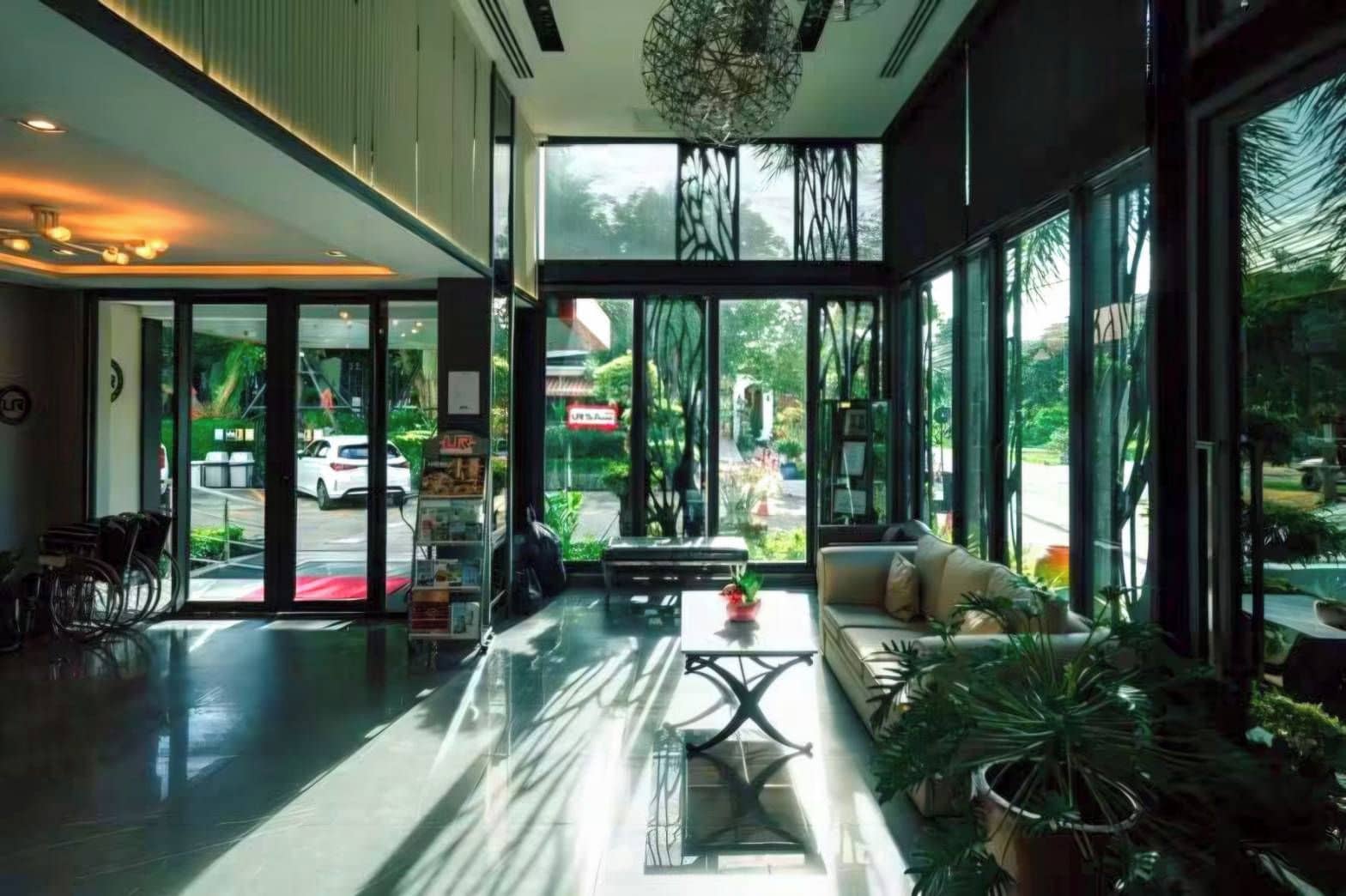 Un hall d’hôtel moderne doté d’un comptoir d’accueil, d’un espace salon et de grandes fenêtres donnant sur la rue.