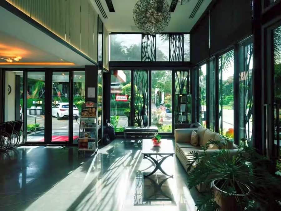 A modern hotel lobby with a reception desk, seating area, and large windows offering views of the street.