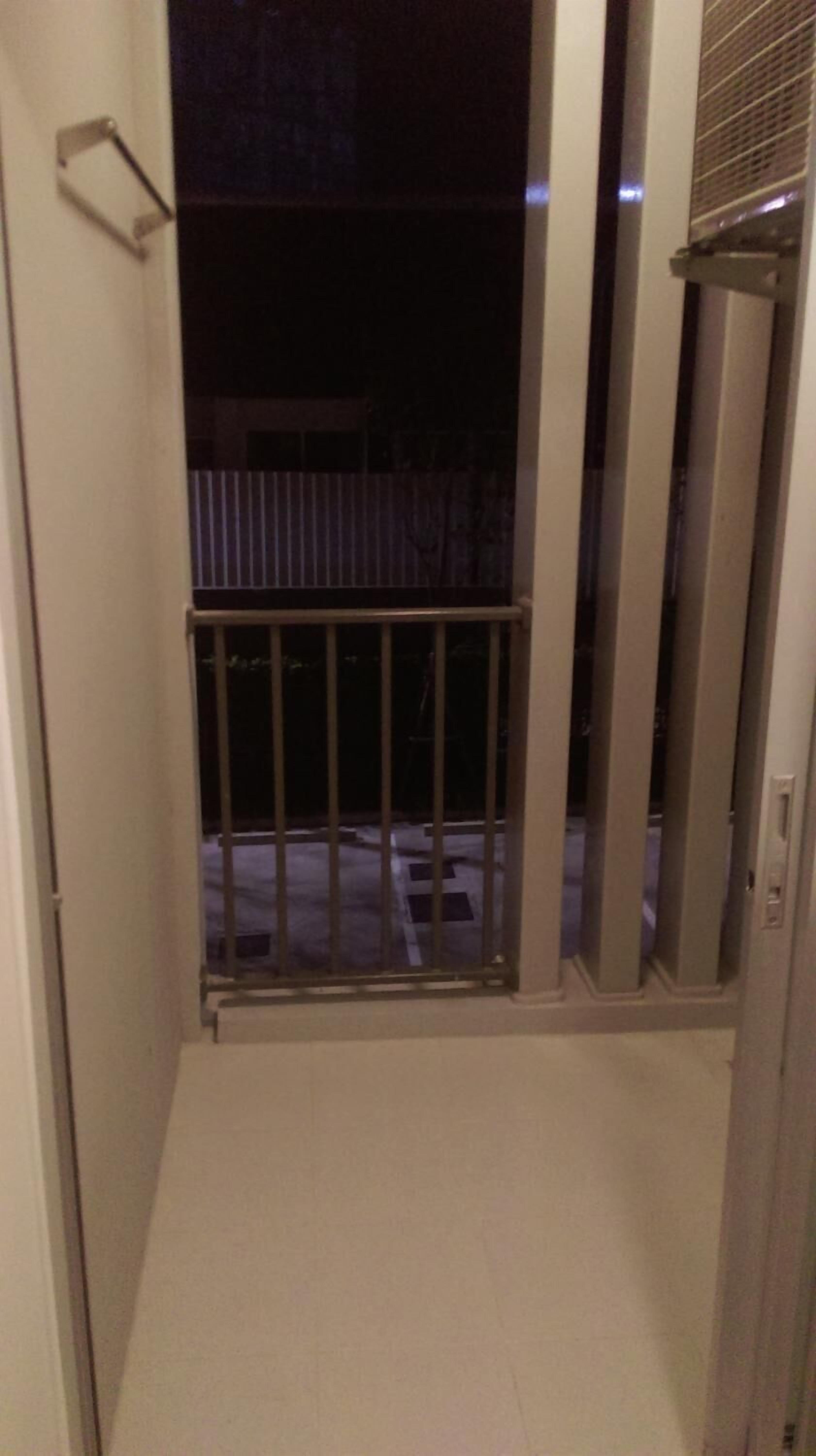 A narrow corridor with a metal gate leading to an outdoor area.