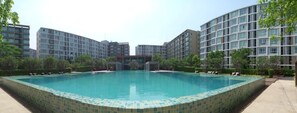 A swimming pool surrounded by modern apartment buildings with a tiled edge. - D Condo Sign Chiang Mai R628 (Chiang Mai)