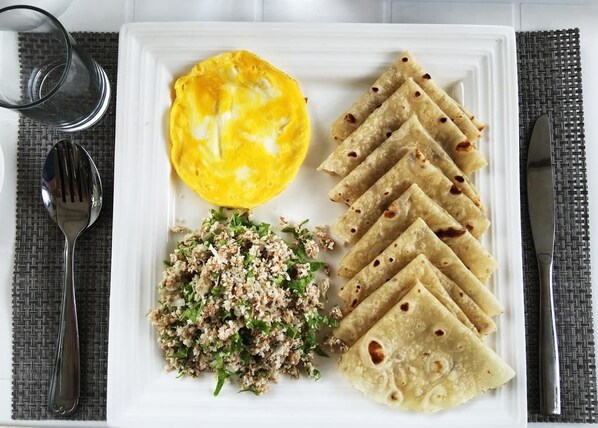 Un plato blanco con una tortilla francesa, tortillas enrolladas y una ensalada.