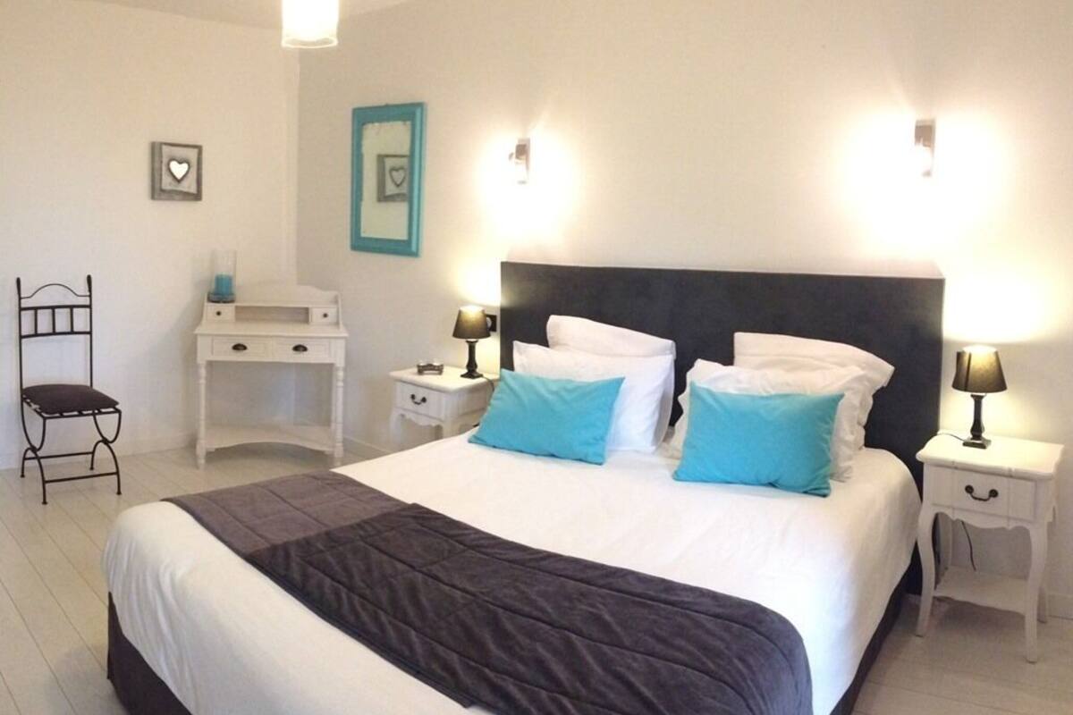 A neatly arranged bedroom with a large bed, two bedside tables, a desk, and a chair.