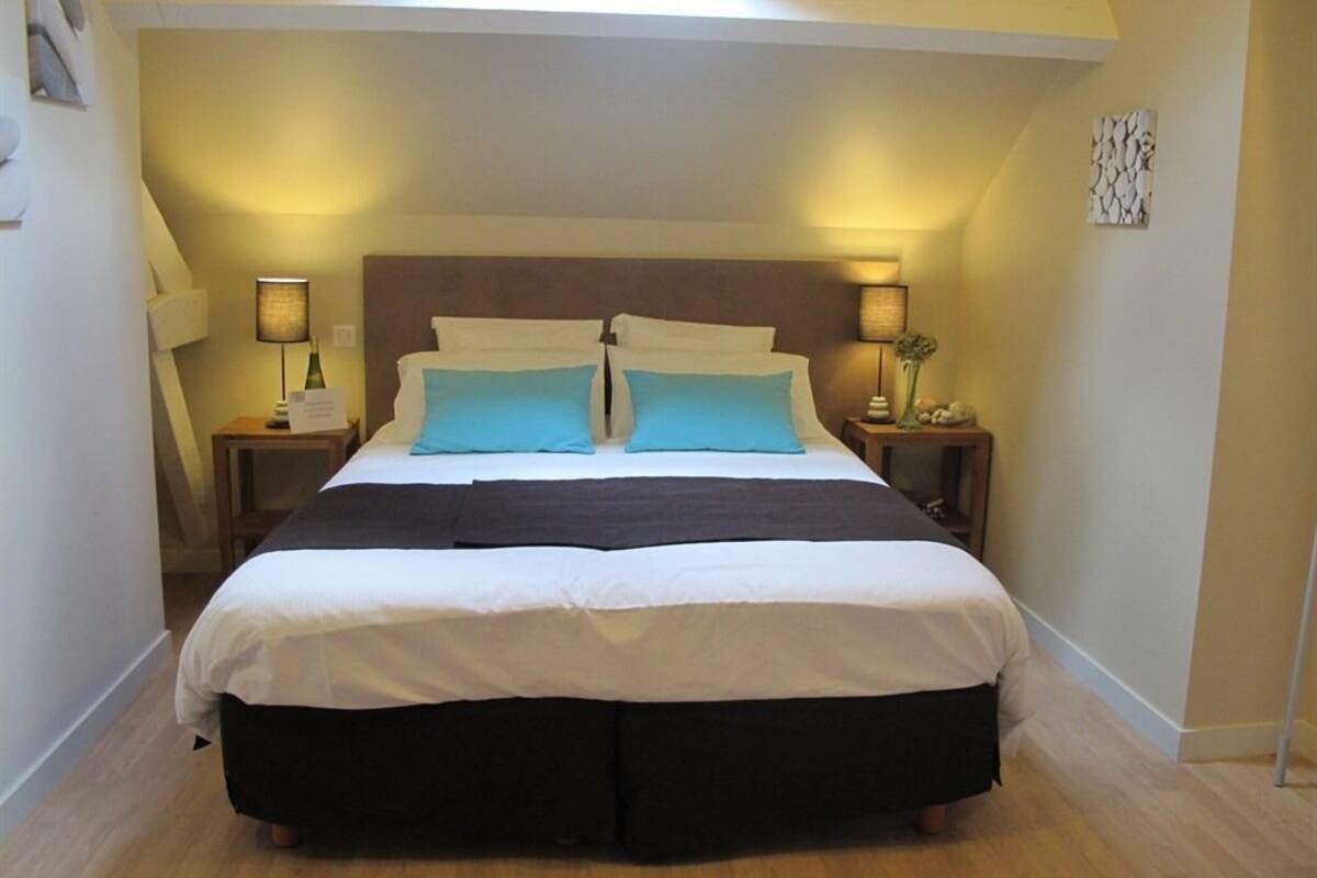 A bedroom with a large bed, two bedside tables with lamps, and a skylight above.