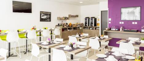 A modern dining area with white chairs and tables, a coffee station, and a purple accent wall.