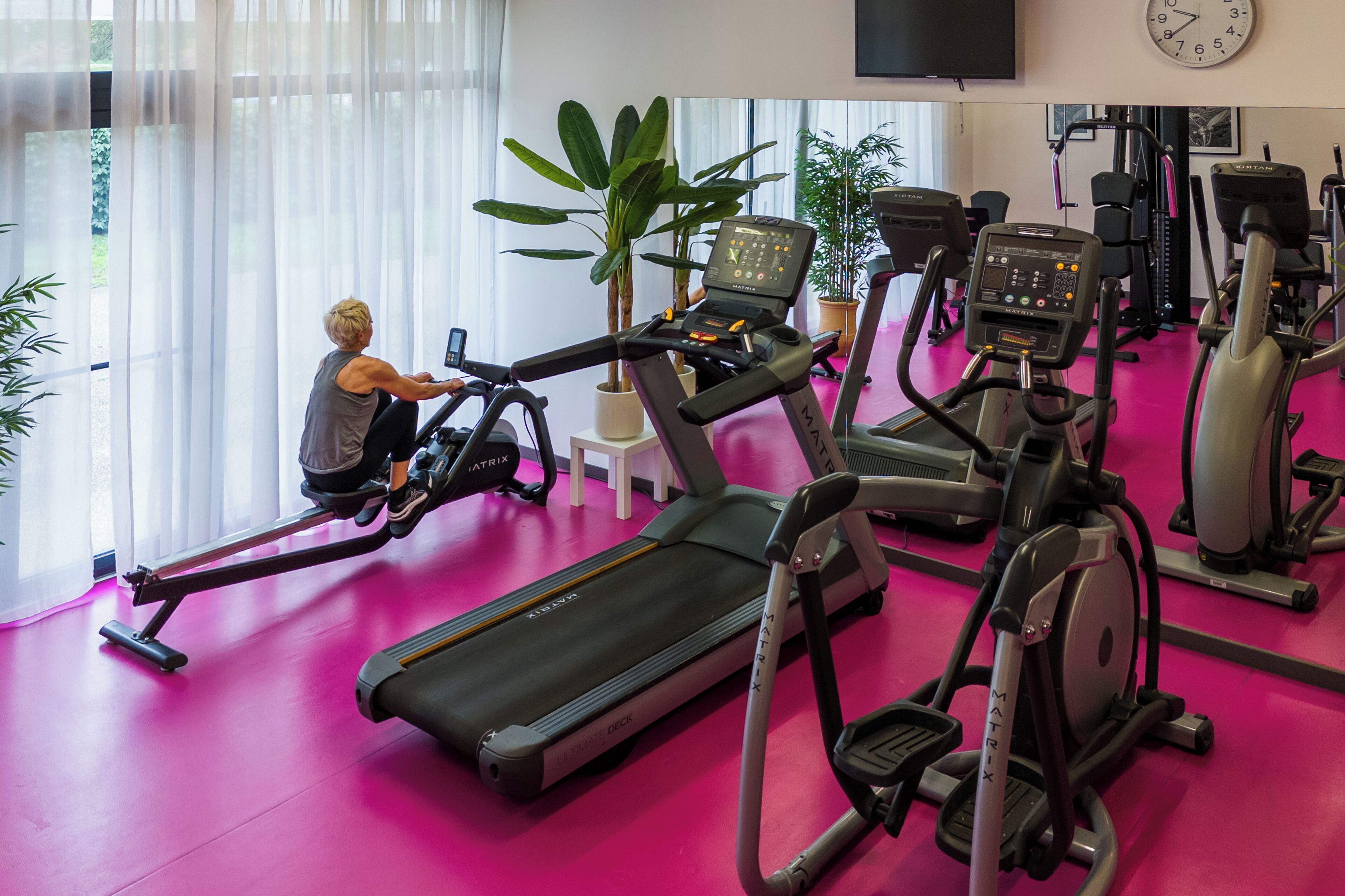 Ein Fitnessstudio mit unterschiedlichen Trainingsgeräten, darunter Rudergerät, Laufbänder und Ergometer.