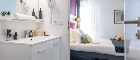 A modern hotel room with a bathroom and a bed.