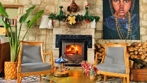 Un salón acogedor con chimenea, dos sillones, una mesita con un carrusel y adornos festivos.