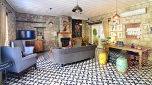 Una sala de estar acogedora con pared de piedra, chimenea, televisor y mostrador de recepción.