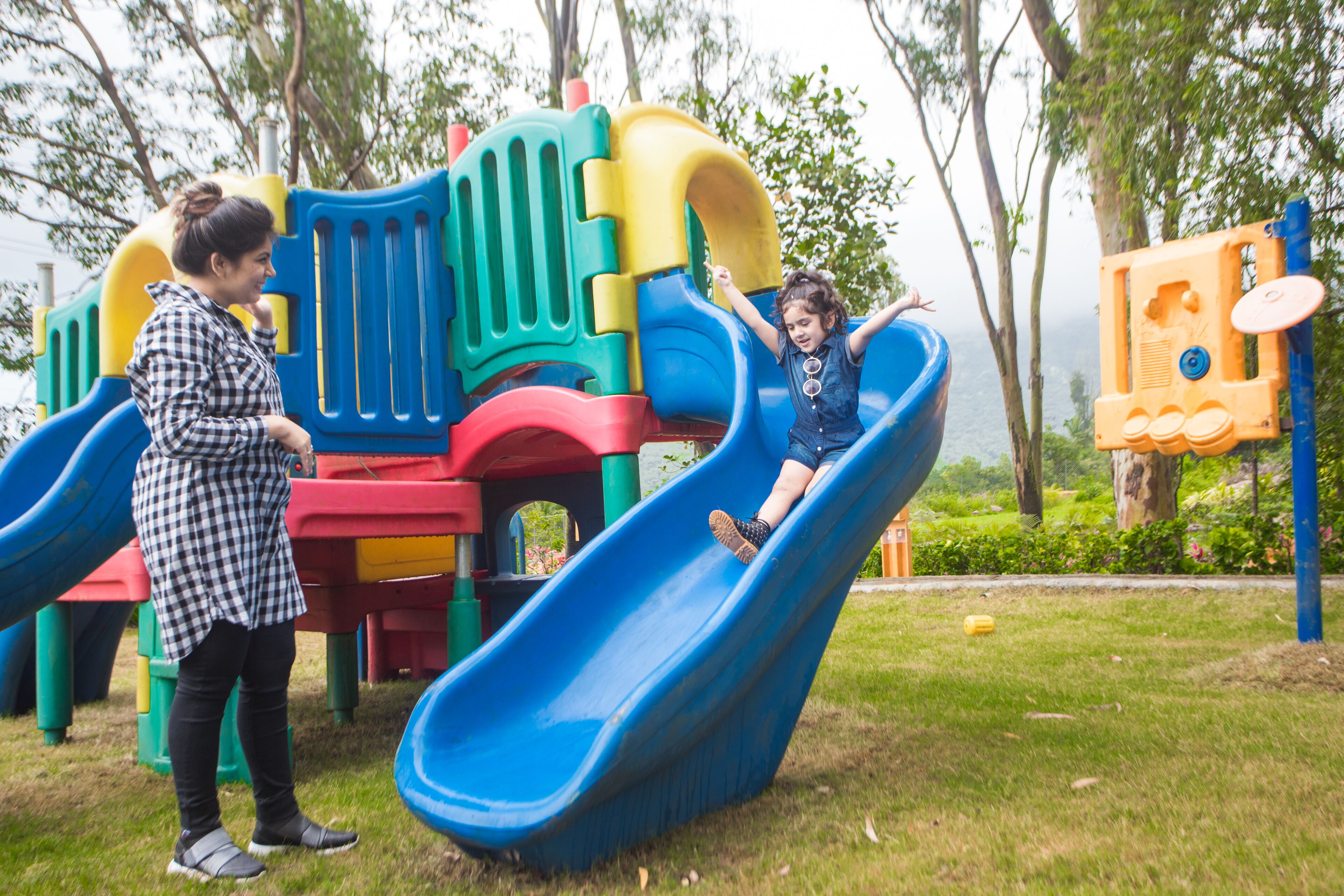 Un parque infantil con un tobogán azul y un niño deslizándose.