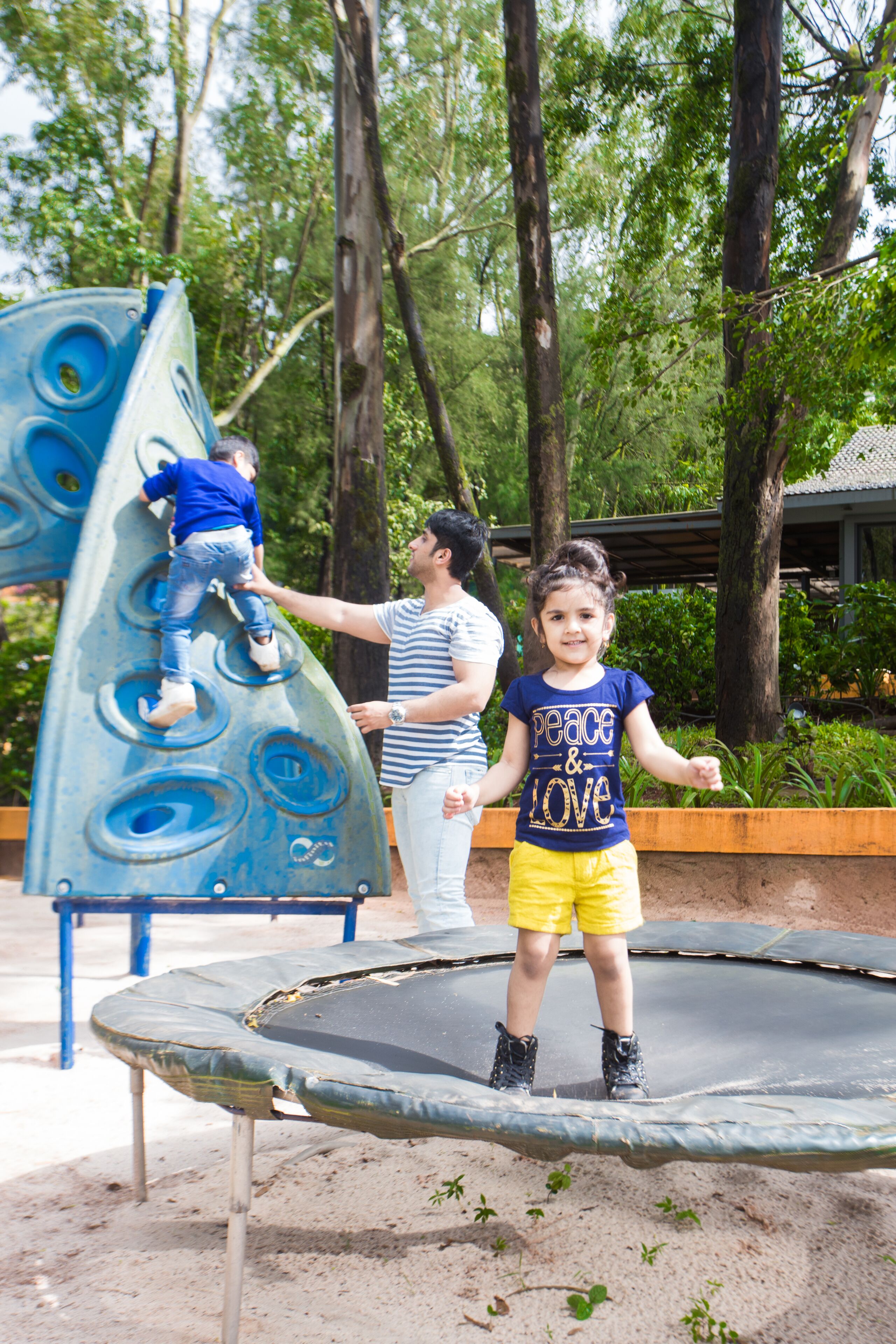 A playground with a climbing structure and a trampoline.