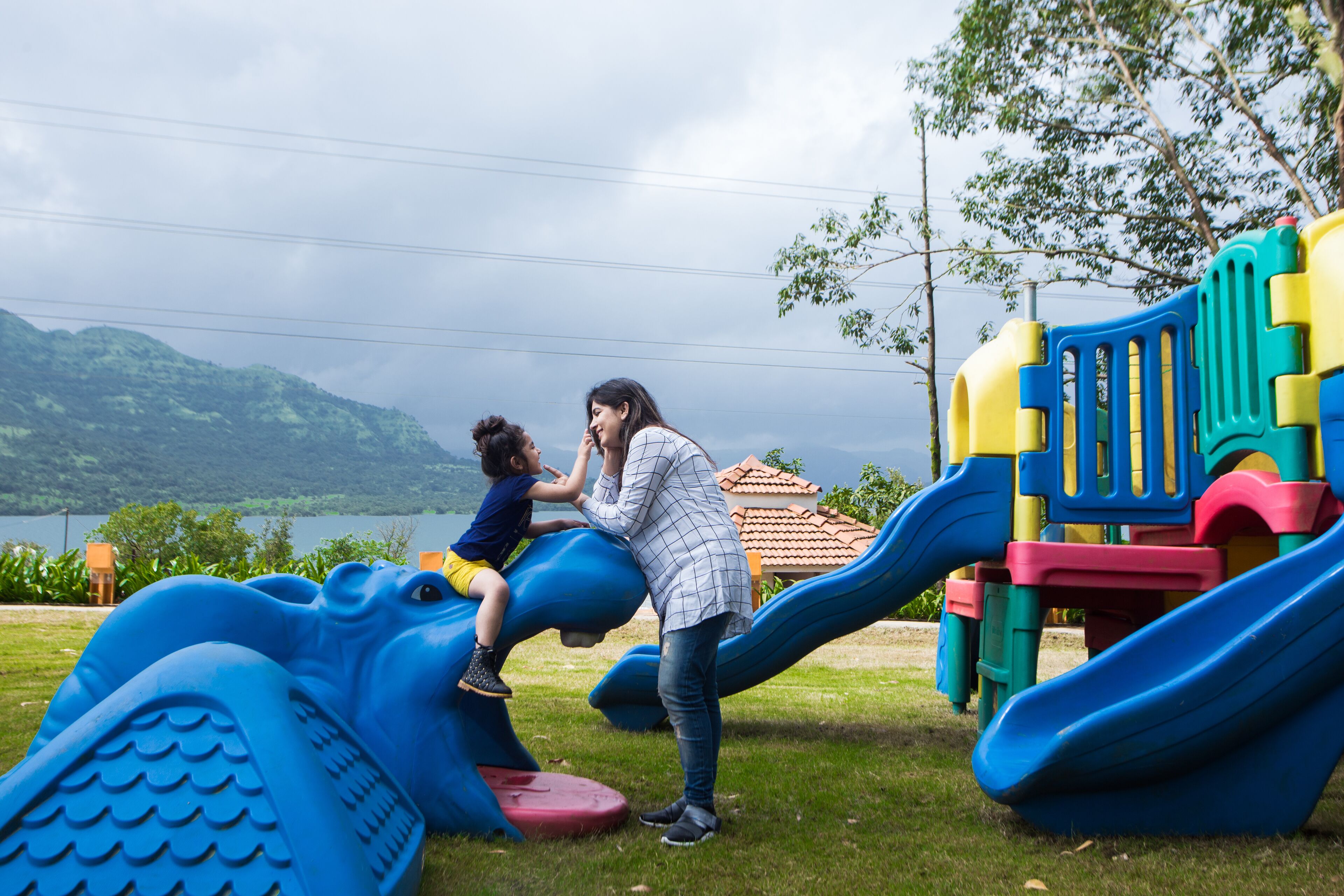 A playground with a blue slide and a child playing on a blue structure.