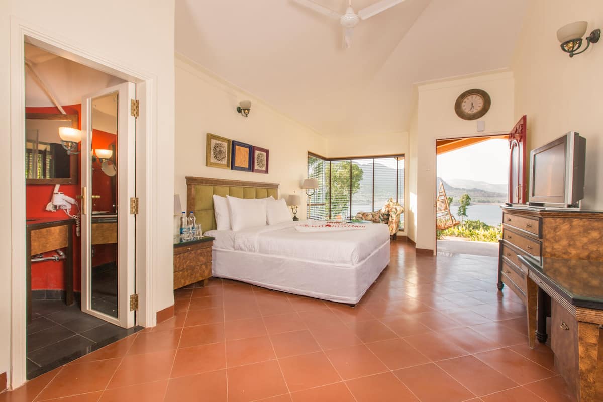 A spacious bedroom with a large bed, a television, and a view of the outdoors.