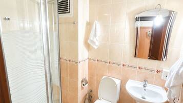 Un baño con cabina de ducha de vidrio, inodoro, lavabo y espejo.