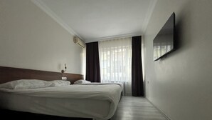 A hotel room with a large bed, a flat-screen TV mounted on the wall, and a window with curtains. - Hotel Altinnal (Izmit)