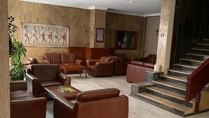 A spacious lobby with leather sofas, a coffee table, a staircase, and a large wall mural. - Hotel Altinnal (Izmit)