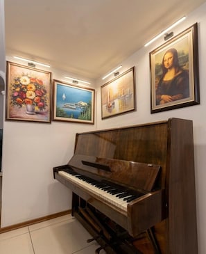 Un pianoforte in un angolo con quattro quadri appesi al muro.