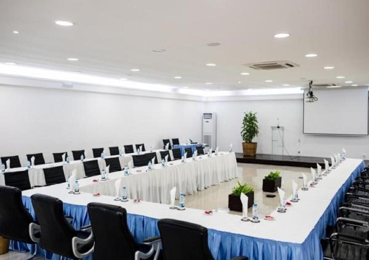 A conference room with a long table, black chairs, and white tablecloths.