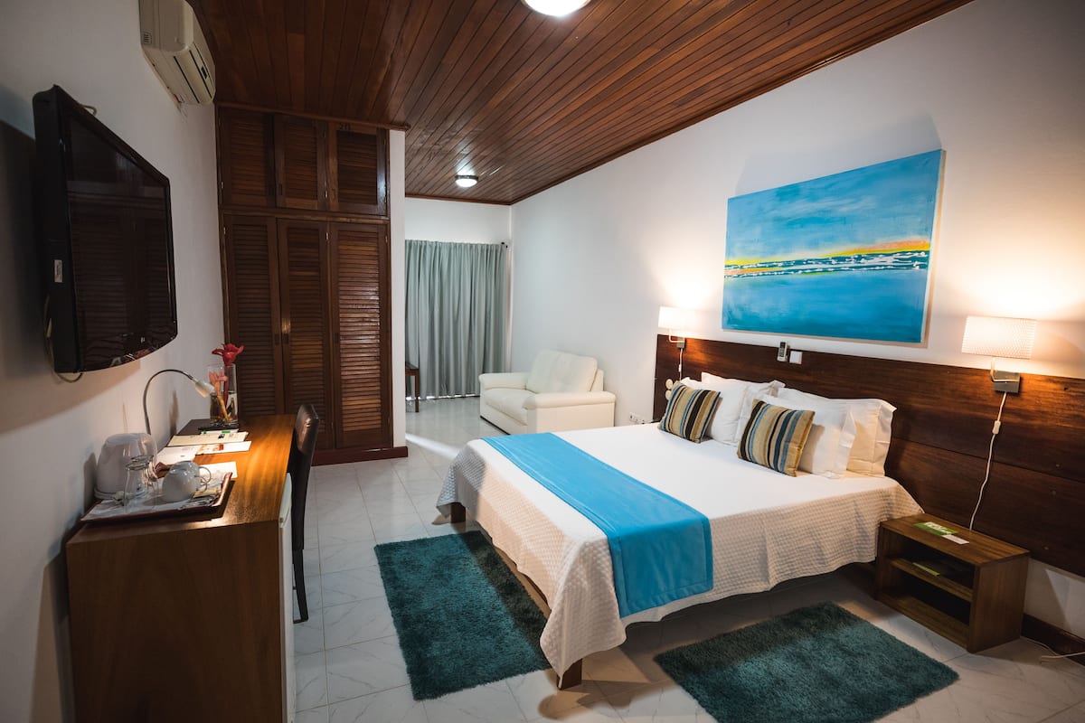 Ein Hotelzimmer mit Bett, Schreibtisch mit Lampe, Fernseher und einem Bild an der Wand.