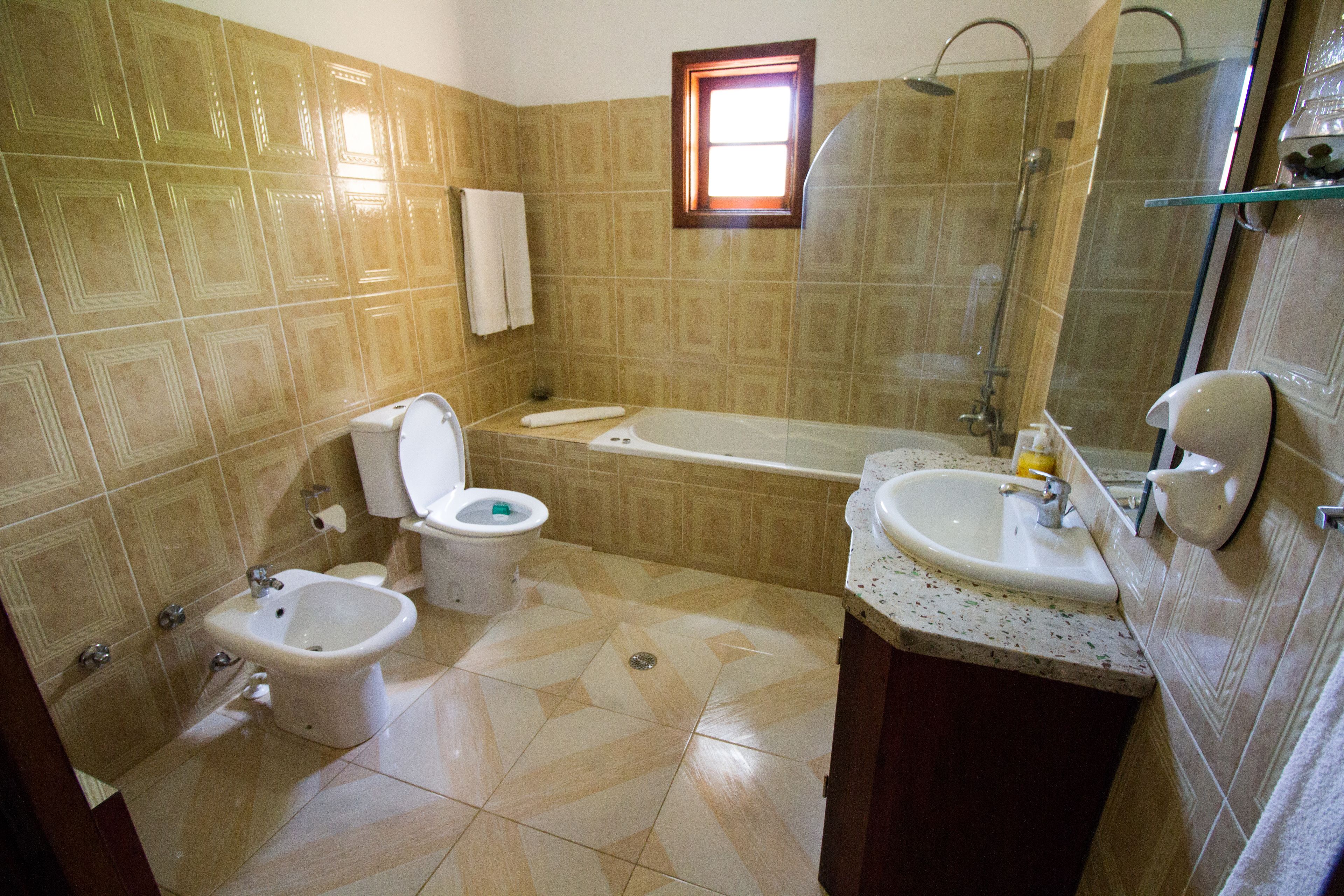 A bathroom with a bidet, toilet, bathtub, and sink.