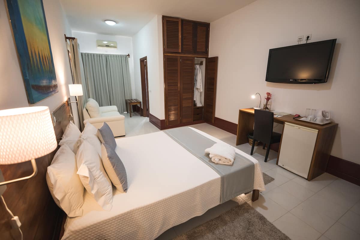 Ein Hotelzimmer mit Bett, Schreibtisch, Fernseher und Kleiderschrank.