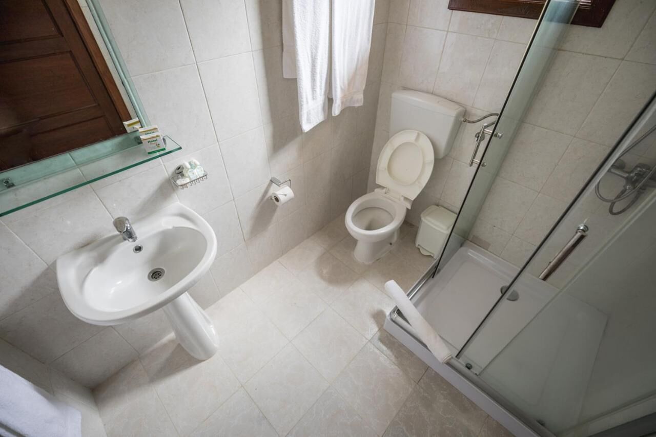 A bathroom with a glass shower enclosure, a pedestal sink, and a toilet.