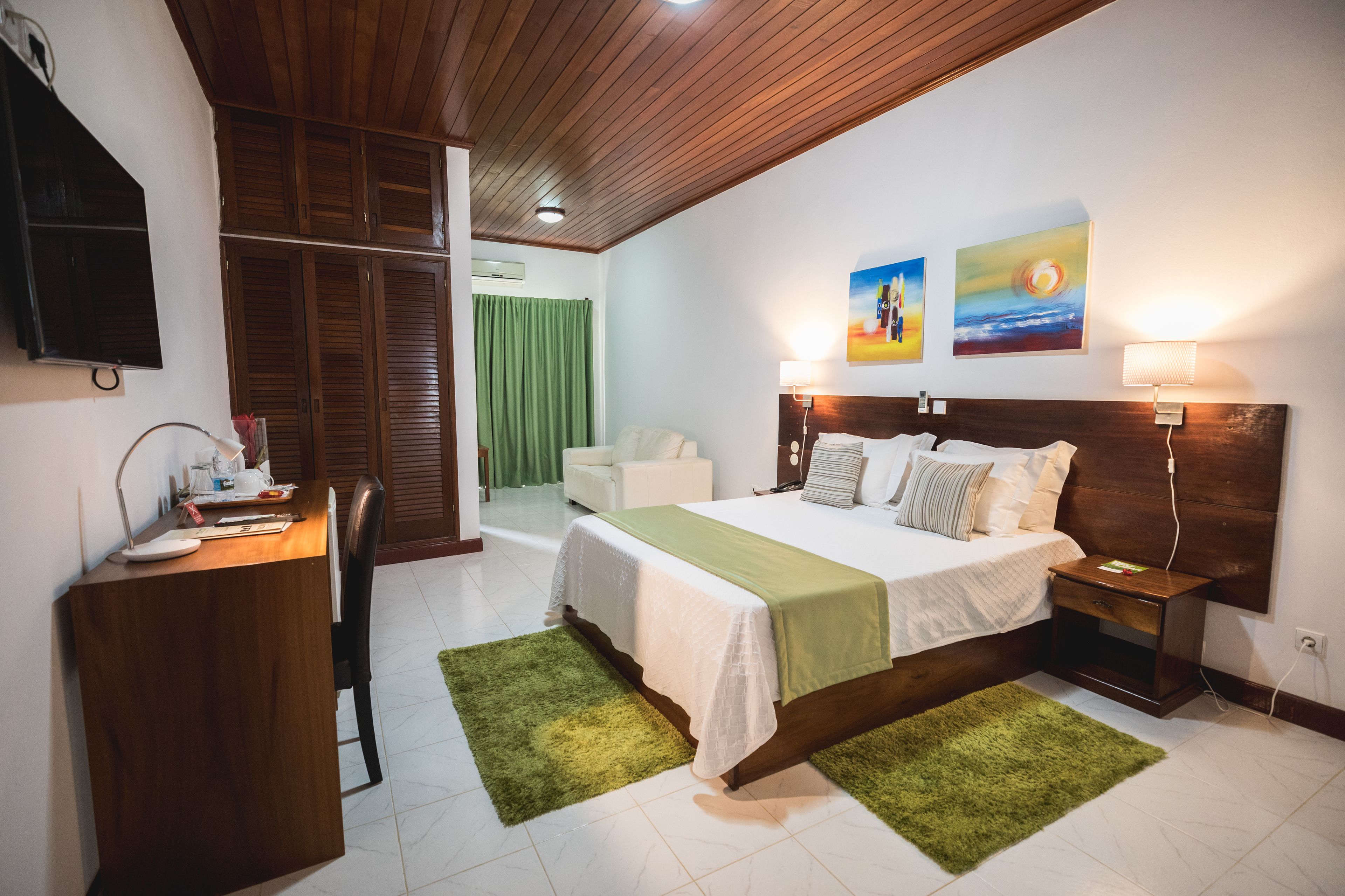 A bedroom with a bed, bedside tables, a desk, and a chair.