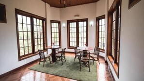 A spacious dining area with a round table and chairs, large windows, and a wooden ceiling. - Hotel Praia (São Tomé)