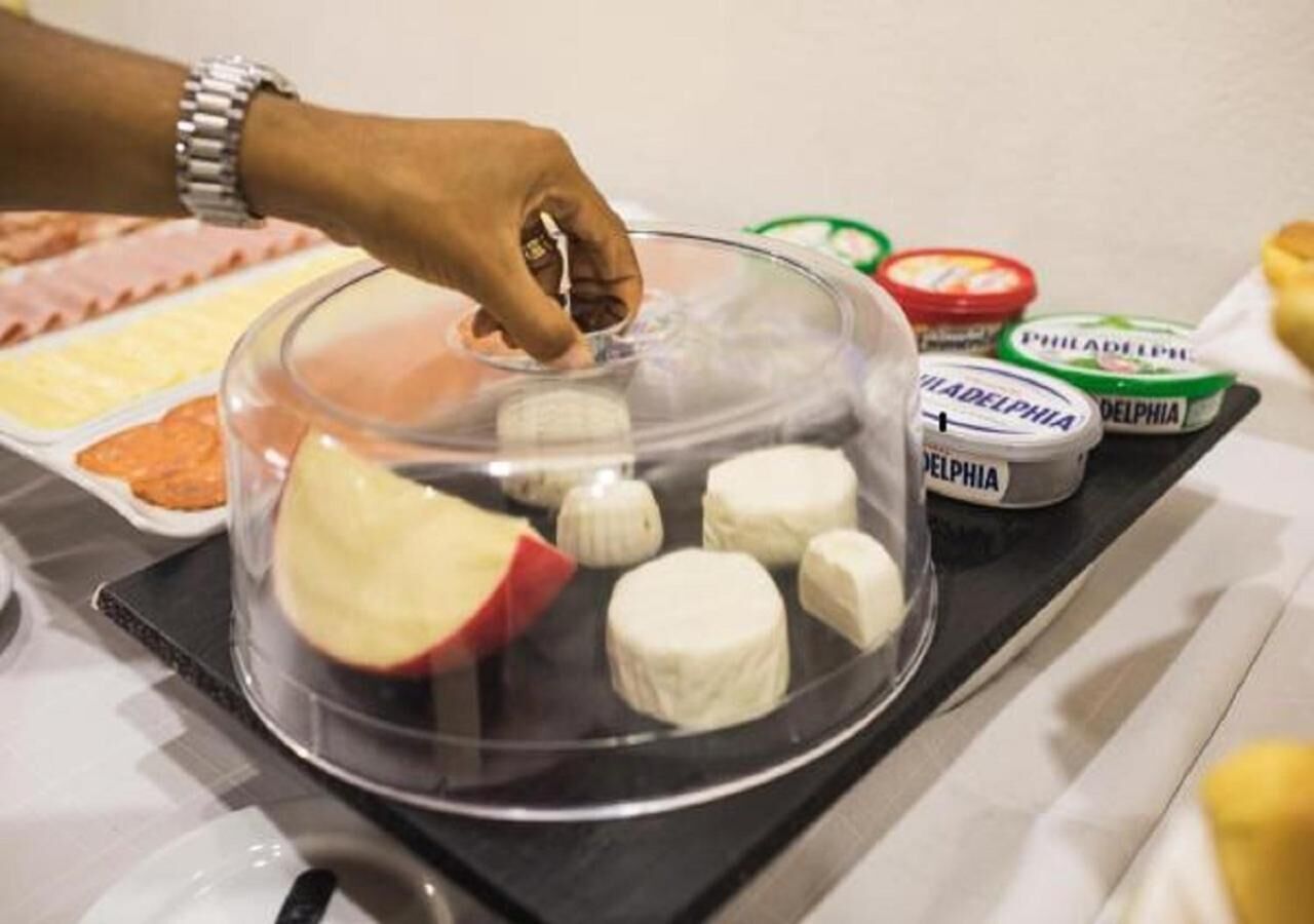 A hand placing a lid on a container with cream cheese and a sliced apple.