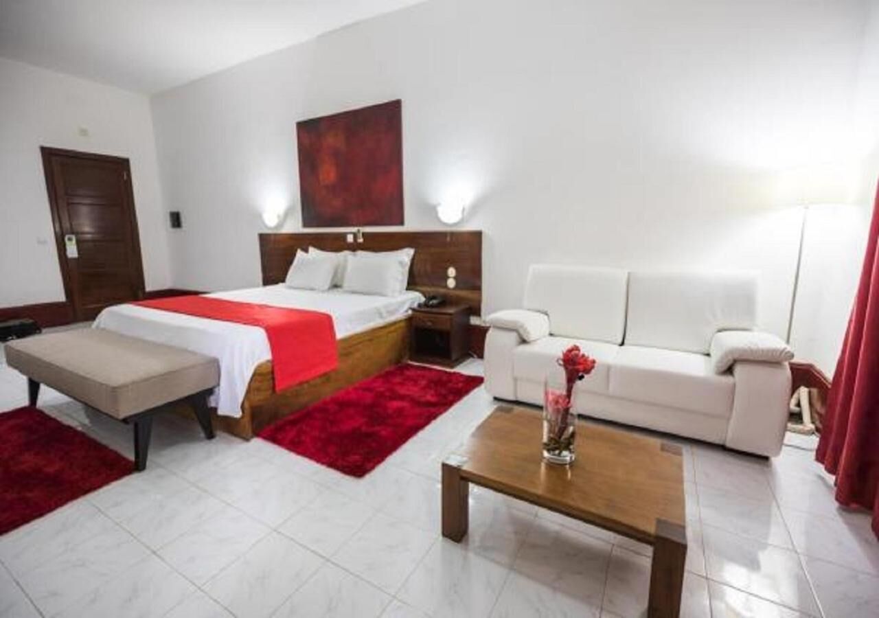 Ein Hotelzimmer mit einem Bett, einem Sofa, einem Couchtisch und einem roten Teppich.