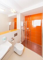 Un baño moderno con ducha de vidrio, lavamanos blanco y retrete.