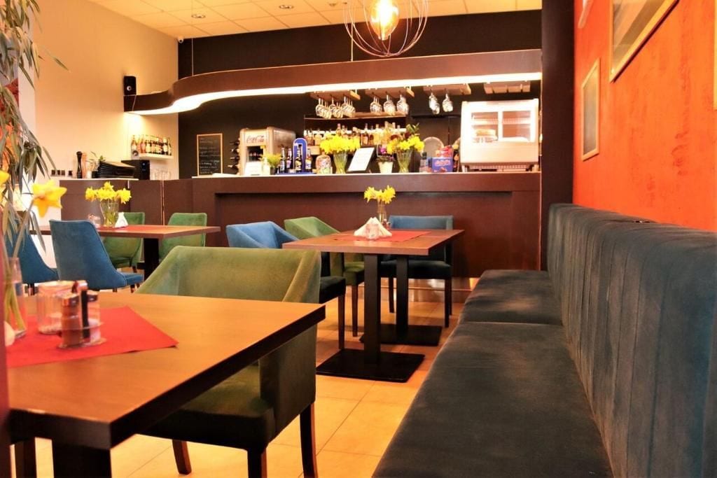 A restaurant interior with tables, chairs, a bar area, and a sofa.
