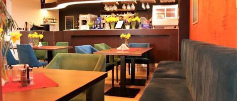 A restaurant interior with tables, chairs, a bar area, and a sofa.