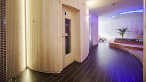 Un cuarto de spa con sauna de madera, una camilla de masaje y una planta pequeña.