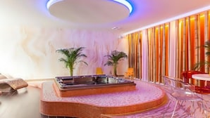 Un moderno espacio de spa con hidromasaje, sillas de vidrio transparente y una pared decorativa con elementos verticales.
