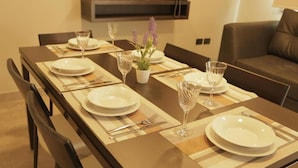 A dining table set with plates, cutlery, and glasses, with a potted plant and a vase of flowers on the table. - Links Apart Hotel (Río Grande)
