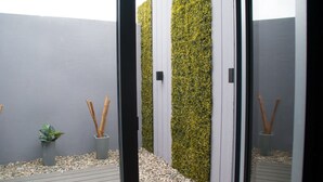 A modern outdoor space with a grey wall, a vertical garden, and a wooden deck. - Links Apart Hotel (Río Grande)