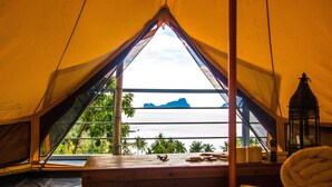 A tent with a view of the sea and mountains, a wooden bench, and a lantern. - The Birdhouse El Nido - Glamping (El Nido)