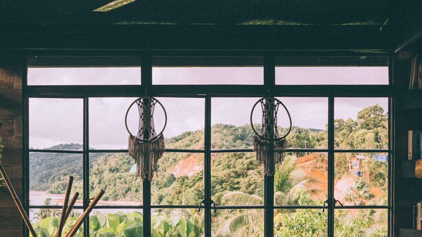 A cozy room with a large window, a ceiling fan, a round table, and a bookshelf. - The Birdhouse El Nido - Glamping (El Nido)