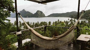 A hammock on a wooden deck overlooking a body of water with mountains in the background. - The Birdhouse El Nido - Glamping (El Nido)