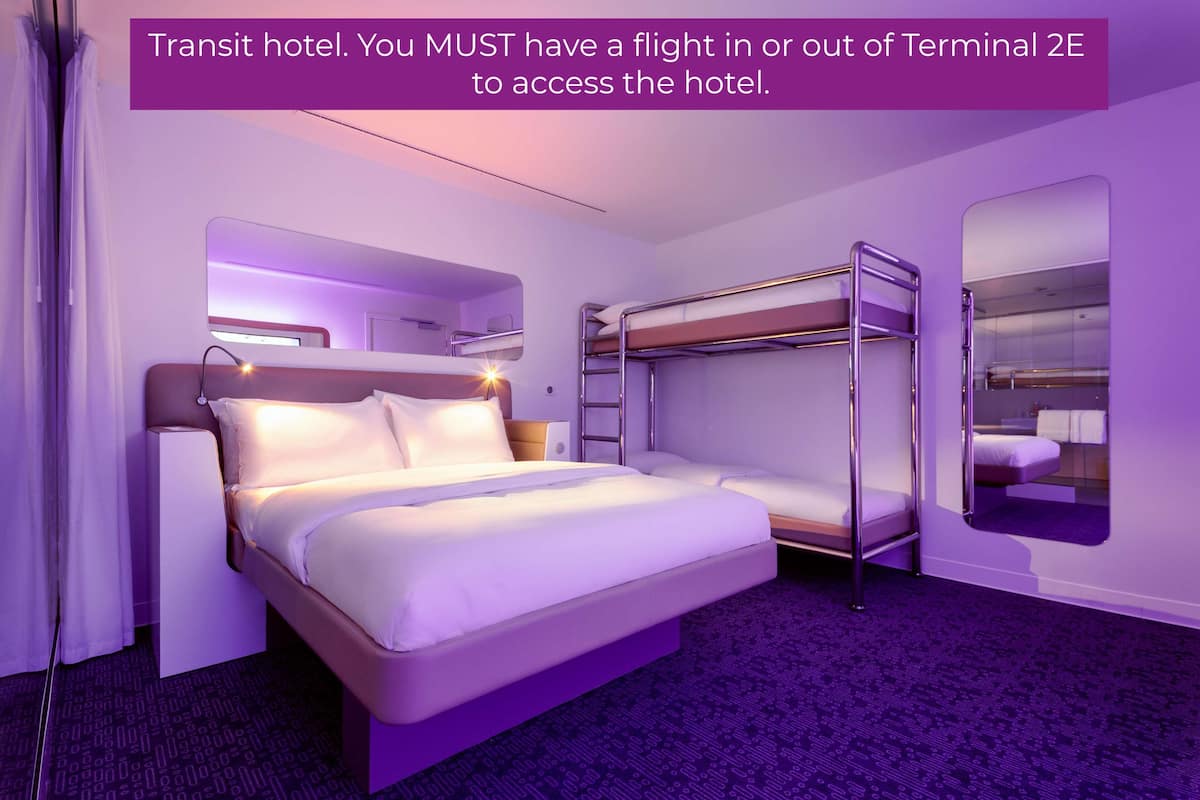 Una habitación de hotel moderna con una cama litera, un escritorio y un espejo grande.