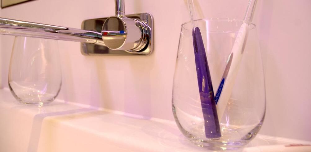 Un lavamanos con grifo y un vaso que contiene un cepillo de dientes.
