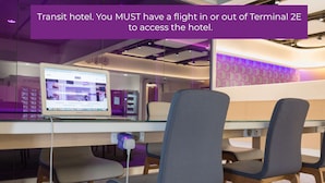 Eine moderne Hotelhalle mit einem Laptop auf einem Schreibtisch, einer Glastrennwand und einer violett beleuchteten Wand.