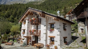 A traditional chalet with stone walls, wooden balconies, and flower boxes. - La Maison d'Antan (Bionaz)