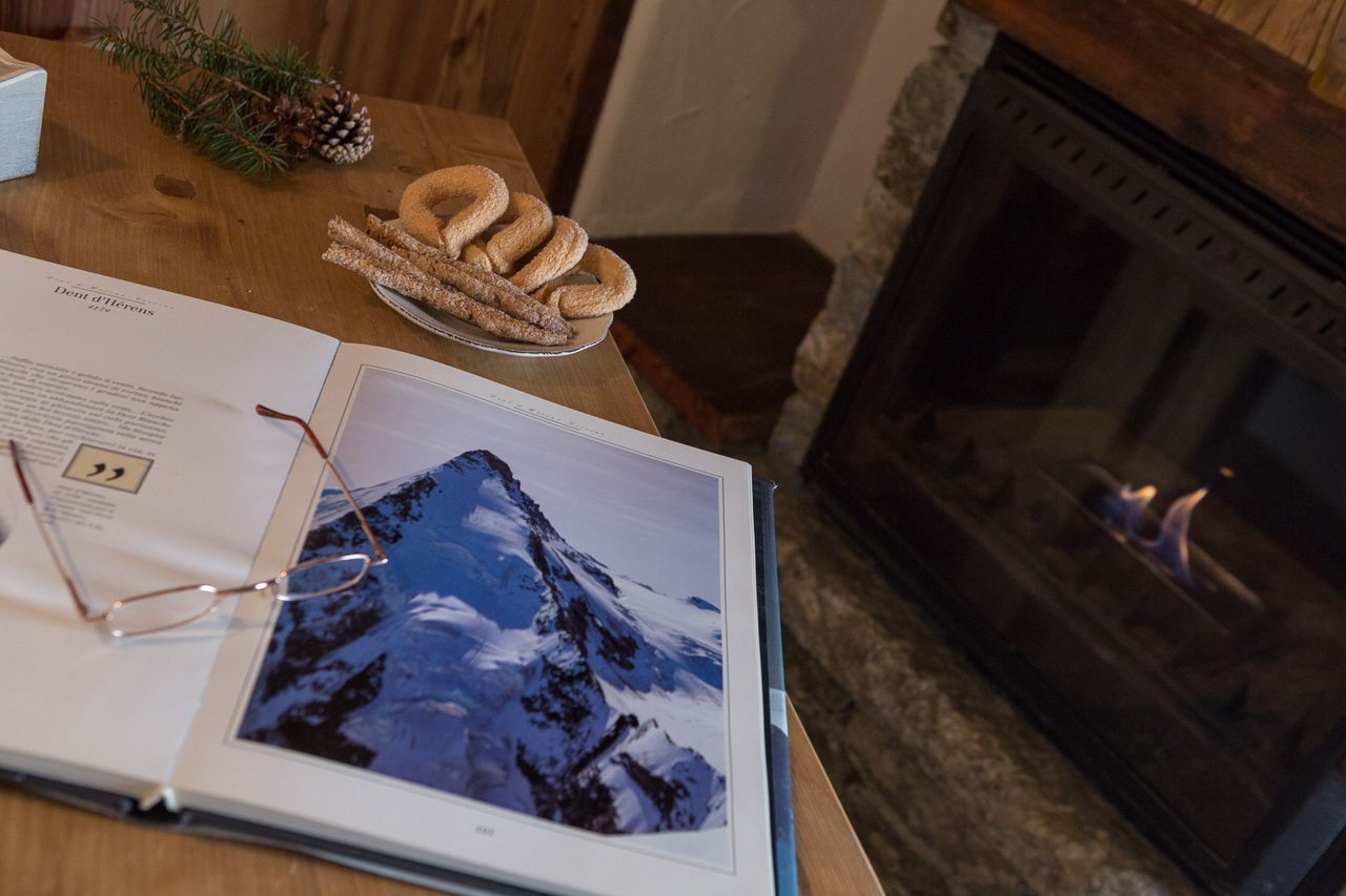Un livre ouvert sur une photographie de montagne, une assiette de churros et une cheminée.