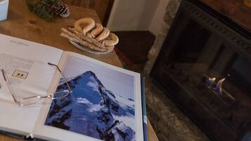 Un livre ouvert sur une photographie de montagne, une assiette de churros et une cheminée.