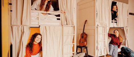 Una camera del dormitorio con letti a castello, una chitarra e uno zaino.